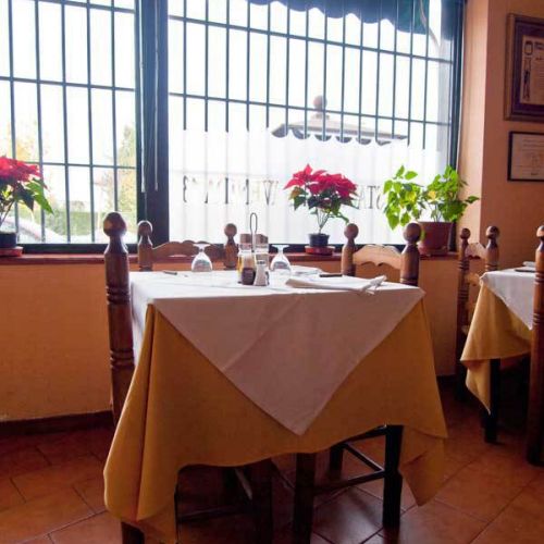 Interior del restaurante con mesa cuadrada, sillas y decoración de flores