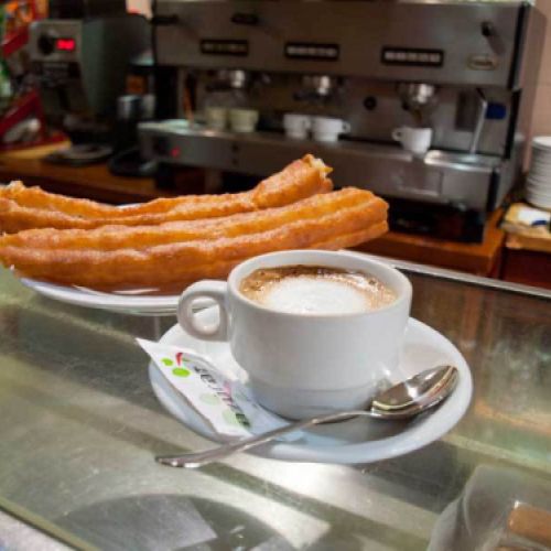 Cafetería con taza de chocolate y porras