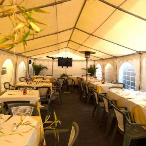 Amplia comedor dentro de carpa en terraza cerrada para celebraciones